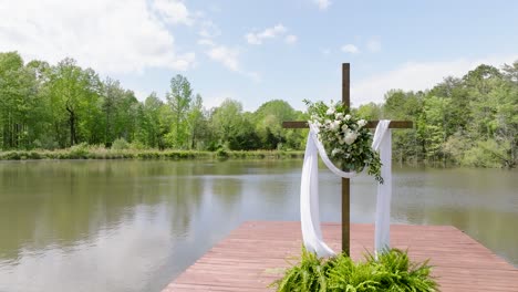 Religious-cross-with-clothe-draped-across-blowing-in-the-wind-on-the-dock-of-a-lake