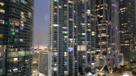 Revealing-shot-of-Downtown-Miami-skyline-office-buildings-and-apartments-at-sunset-illuminated-with-light,-Slow-motion-Aerial