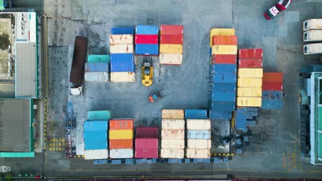 Drone-aerial-view-of-palm-oil-kernel-factory-warehouse-with-cargo-container-and-forklifts,-at-Malaysia