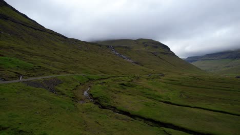 Car-driving-in-the-distance-along-foggy-mountain-road,-Faroe-Islands
