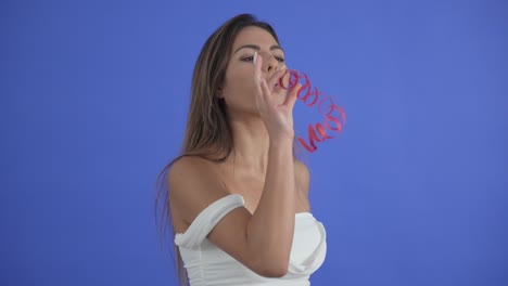 Schönes-Mädchen-Bläst-Einen-Roten-Party-Streamer,-Isoliert-Auf-Blauem-Hintergrund