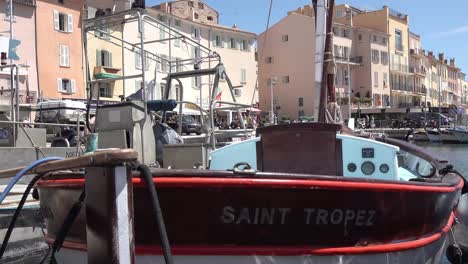 Old-port-of-Saint-Tropez-with-fishing-boat-in-the-foreground-and-restaurants-in-the-background