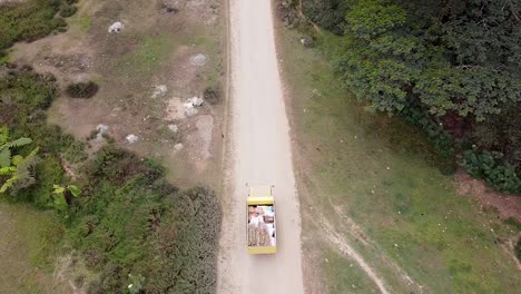Aerial-birds-eye-view-of-yellow-truck-delivering-food-and-drink-supplies-in-the-remote-districts-of-Timor-Leste-in-Southeast-Asia