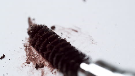 Blending-a-dark-brown-toned-mascara-loose-powder-using-an-eyelash-wand-applicator-on-a-blank-white-board