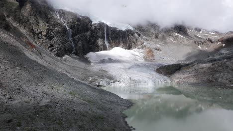 Lengua-Glaciar-Fellaria-Y-Laguna-Con-Montañas-Rocosas-Envueltas-En-Nubes-En-El-Fondo,-Valmalenco-En-Italia