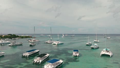 Drone-flying-over-boats-and-catamarans-moored-in-Bayahibe-Bay,-La-Romana-in-Dominican-Republic
