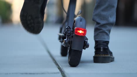 close-up-shot-of-the-backlight-of-an-e-scooter-while-someone-gets-on-and-drives-off