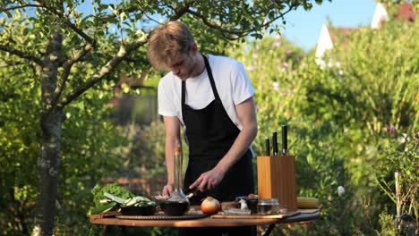 young-man-preparing-things-for-grilling-on-a-wooden-table-in-his-garden