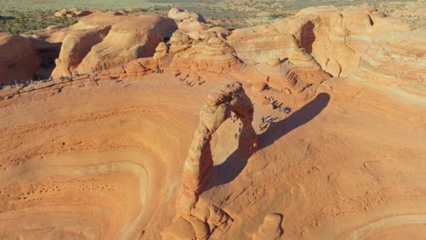 Vista-Aérea-De-Personas-Caminando-Hacia-Las-Formaciones-Rocosas-De-Arenisca-En-El-Parque-Nacional-Arches,-Utah,-EE.UU.