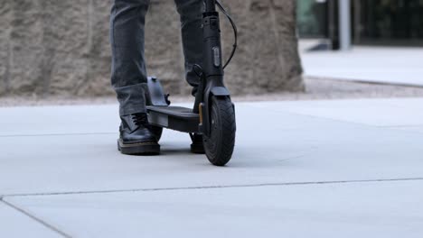Close-up-of-a-businessman-walking-to-his-e-scooter-and-driving-off