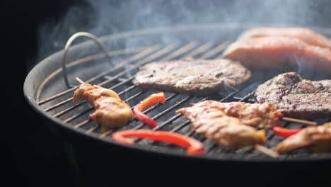 Slow-motion-shot-of-a-grill-with-steak,-chicken-skewers,-peppers-and-salmon