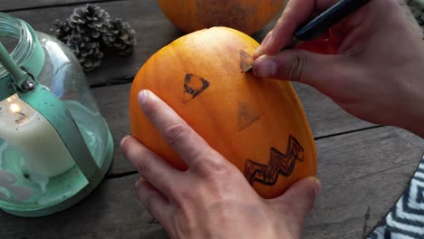 Close-up-of-male-hand-carving-the-eyes-of-jack-o-lantern-for-halloween