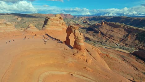 Aerial-View-Of-Delicate-Arch-With-Tourists-In-Arches-National-Park,-Utah,-USA---drone-shot