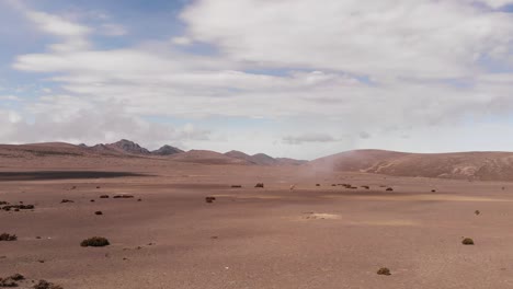 Sand-flying-over-the-dunes-of-the-Chimborazo-desert-in-Ecuador,-llamas-appear-in-the-scene