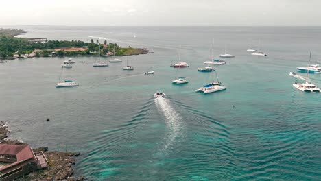 White-wake-trail-of-speedboat-navigating-over-calm-sea-water-in-Bayahibe-port,-La-Romana-in-Dominican-Republic