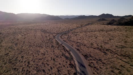 drone-flying-into-sunset-over-empty-road-in-joshua-tree-california