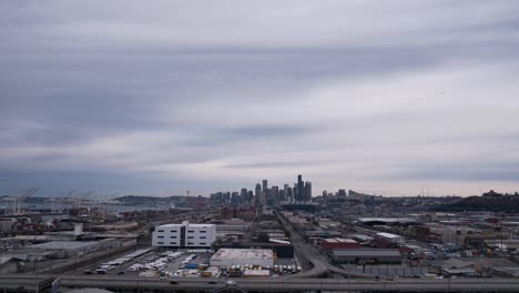 Aerial-Hyper-lapse-of-Seattle-city-skyline,-Smooth-dark-clouds-undulate,-traffic-rushes-past