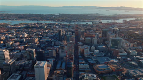 Aerial-view-of-Downtown-Oakland-Skyline-And-San-Francisco-Bay-During-Sunset-In-California,-United-States