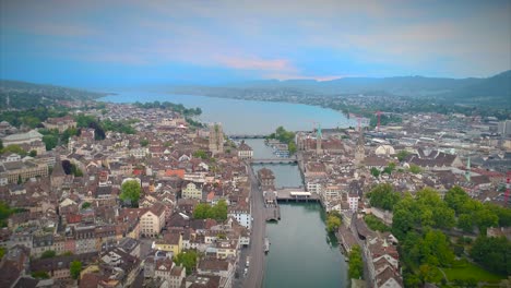 Aerial-Push-In-Zurich-Switzerland-Establishing-Shot-Church-Europe-Water-River-Stream-Statue-Bridge-Europe-Steeple-Walkway-People-Urban-Architecture-4K-Tourist-Destination-View-Swiss-Town