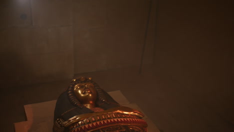 A-golden-mummy-sarcophagus-laying-in-a-chamber-in-a-tomb-in-the-pyramids-in-a-beam-of-light