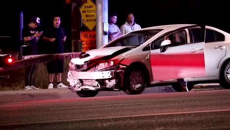 Car-accident-totaled-a-Honda-sedan-along-the-highway-with-ambulance-lights,-handheld