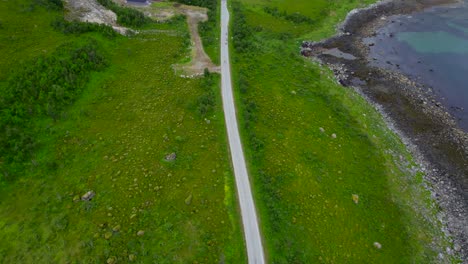 Revealing-shot-of-Senjahopen-with-bicycle-driving-along-the-scenic-route-on-a-overcast-summer-day,-Senja-Island