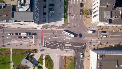 Aerial-top-down-shot-of-driving-bus-and-cars-on-road-junction-in-Gnom-City-at-Sunny-day