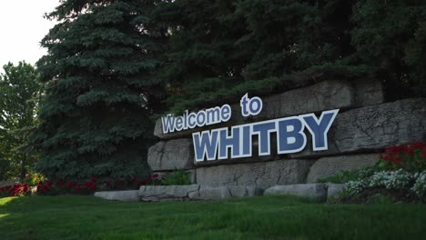 Willkommen-In-Whitby,-Kanada-Schild-Mit-Sonnenschein,-Der-Durch-Die-Bäume-In-Einem-Botanischen-Garten-Mit-Niedrigem-Schwenk-Schimmert