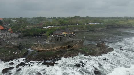 Aerial-view:-Grey-ocean-waves-splash,-crash-on-rocks-at-Tanah-Lot-Bali