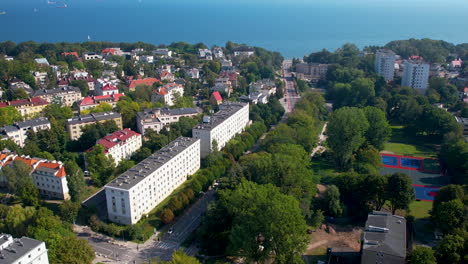 Rückwärtsaufnahme-Aus-Der-Luft,-Die-Die-Wunderschöne-Stadt-Gdynia-Mit-Park-Und-Bäumen-Und-Der-Blauen-Ostsee-Im-Hintergrund-Zeigt