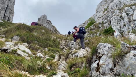 Low-Angle-Aufnahme-Von-Touristen,-Die-An-Einem-Bewölkten-Tag-Selbstbewusst-Den-Felsigen-Berghang-In-Brasov,-Rumänien-Entlang-Klettern