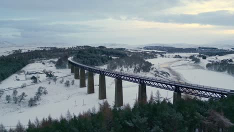Aerial-ascending-footage-of-snowed-valley-and-famous-historic-Findhorn-Viaduct-over-it