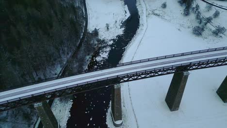 High-angle-view-of-old-railway-bridge-and-frozen-river-in-winter-countryside