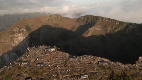 Aerial-pan:-Tourists-on-rim-of-Mount-Batur-volcano-crater-at-sunrise