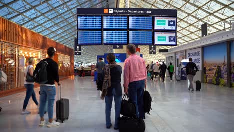 Group-of-people-with-luggage-getting-ready-to-travel-watching-the-screens-announcing-their-flights,-Paris-Airport,-France