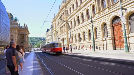 Red-trolley-car-with-wires-and-tracks-laid-on-sunlit-streets-on-a-clear-day-in-Prague,-Czech-Republic