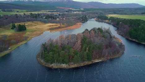 Aerial-slide-and-pan-footage-of-colorful-trees-on-island-surrounded-by-rippled-water-surface-of-river