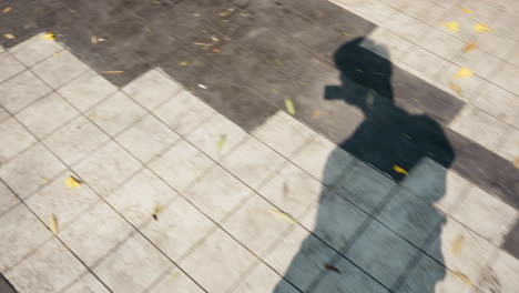 Shadow-of-man-content-creator-vlogging-camera-on-sunny-day-walking-handheld