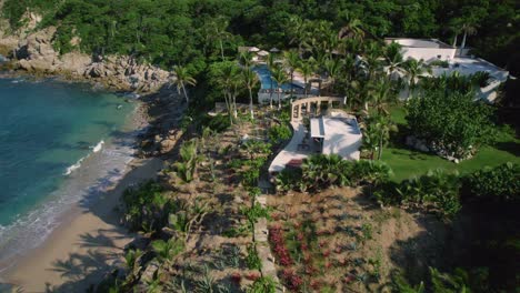 Aerial-drone-view-on-a-sunny-day-revealing-a-beautiful-beach-resort-with-luxury-homes-nearby-the-shore-palm-trees