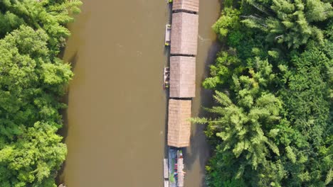 Top-down-aerial-view-of-several-floating-hotels,-on-the-River-Kwai-surrounded-by-jungle,-Kanchanaburi,-Thailand