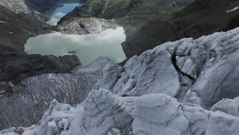 Drone-flying-at-low-altitude-over-surface-of-Fellaria-Glacier-with-lagoon-in-background,-Valmalenco-in-Italy