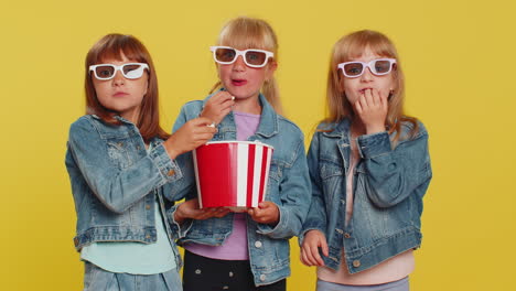 Three-girls-siblings-friends-wearing-3D-glasses-eating-popcorn-watching-interesting-tv-serial-film
