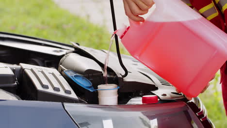 Service-worker-man-pouring-car-fluid-windscreen-red-cleaning-washer-glass-summer-or-winter-cleaner