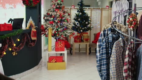 Dolly-In-Der-Aufnahme-Eines-Festlichen-Bekleidungsgeschäfts,-Gefüllt-Mit-Wunderschön-Geschmücktem-Weihnachtsbaum,-Lametta-Girlanden,-Roten-Geschenkpaketen-Und-Anderen-Ornamenten-Während-Der-Winterferienzeit