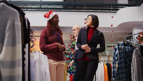 Ground-level-shot-of-customer-spinning-around-in-festive-decorated-clothing-store,-excited-to-show-african-american-employee-elegant-blazer-fitting-perfectly-after-trying-it-on