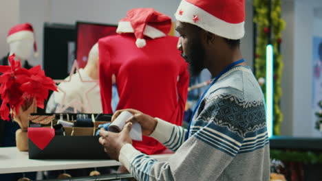Close-up-shot-of-cheerful-african-american-worker-arranging-formal-neckties-in-Christmas-decorated-luxurious-shopping-mall-clothing-store,-making-sure-they-are-ready-for-arriving-clients