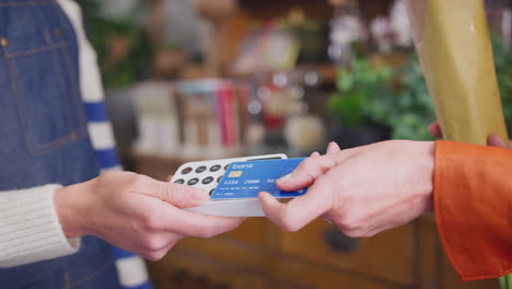 Close-Up-Of-Female-Customer-In-Florists-Shop-Making-Contactless-Payment-For-Flowers-With-Card