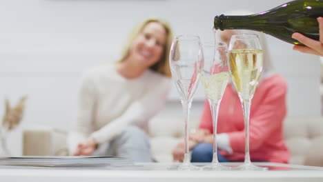 Nahaufnahme-Von-Champagner-Oder-Prosecco,-Die-In-Gläser-Gegossen-Werden,-Mit-Zwei-Frauen-Im-Hintergrund