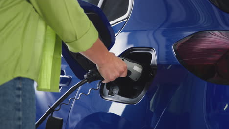 Close-Up-Of-Woman-Attaching-Charging-Cable-To-Environmentally-Friendly-Zero-Emission-Electric-Car
