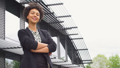 Portrait-Of-Smiling-Businesswoman-Standing-Outside-Modern-Office-Building